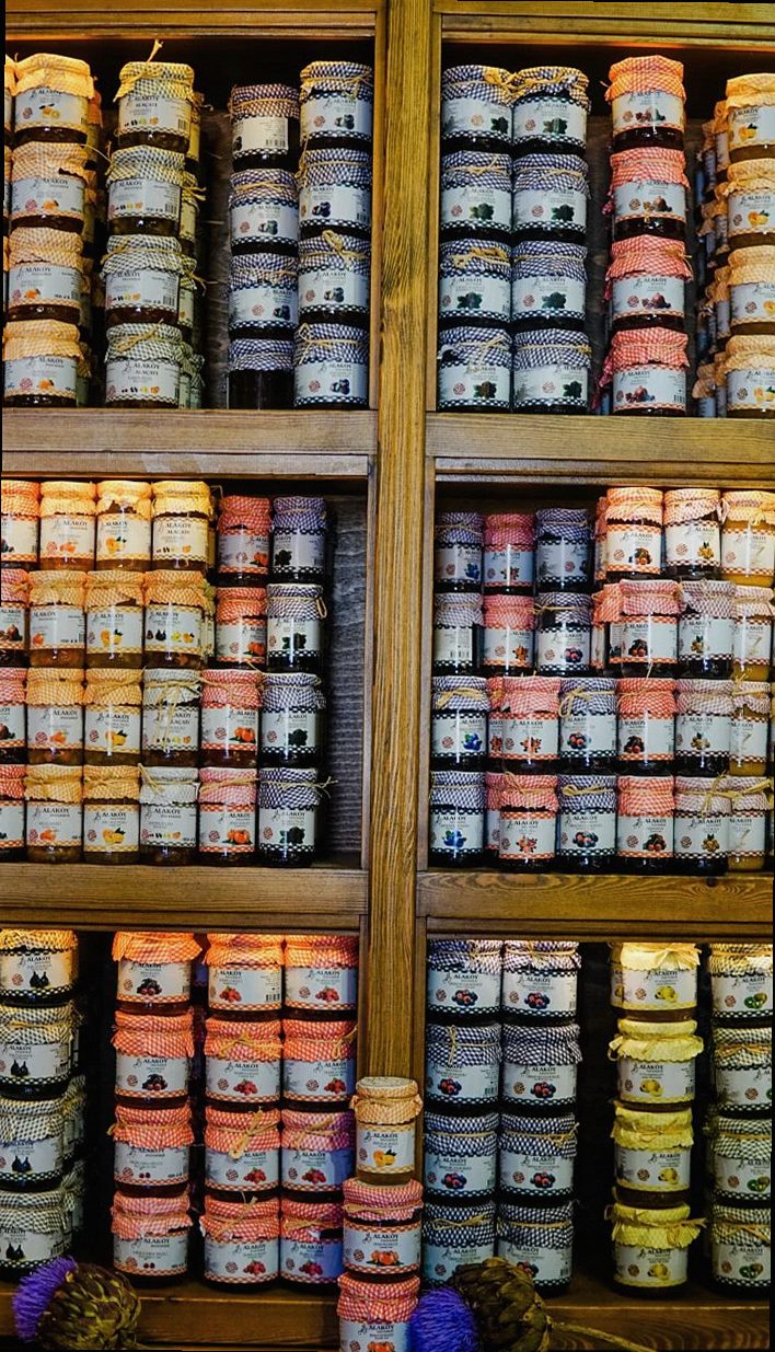 Colorida colección de frascos de mermelada variados ordenados en estantes de madera, con diversos colores y patrones.
